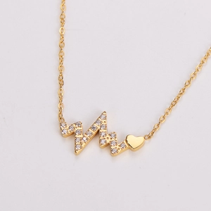 Macro shot of gold heartbeat necklace pendant with sparkling white cubic zirconia stones