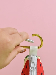 Detail of watermelon pet waste bag dispenser with golden metal carabiner and zipper