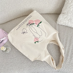 Detail of artistic peach print and motivational text on a cream canvas tote bag