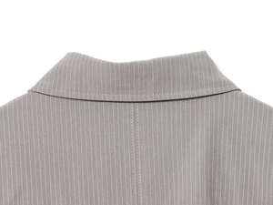 Detailed close-up of striped lapel and stitching on a taupe bomber jacket