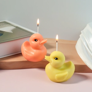 Pair of cute 3D duck shaped scented candles in yellow and orange on a wooden stand