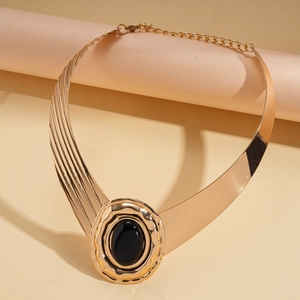 Macro shot of chunky gold choker featuring an oval black resin stone with wavy metal borders