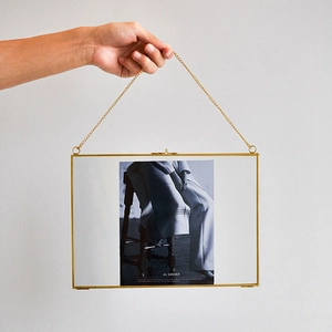 Detail of a golden brass hanging frame with a sturdy metal chain and a secure press-lock
