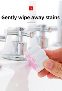 Close-up of pink cat paw cleaning sponge removing stains on a white bathroom sink