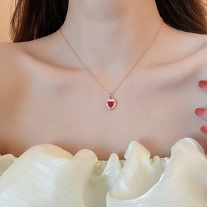 Primo piano della collana a cuore in oro 18K con ciondolo in gemma rossa su modella elegante