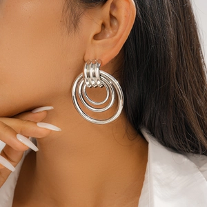 Detail of large silver geometric hollow hoop earrings worn by a model on the ear