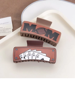 Detail view of western style hair claws with brown leather texture and poker card patterns