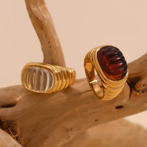 Detail of 18K gold-plated rings with transparent and red stones on natural wood