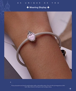 Close-up of a silver snake chain bracelet featuring a pink heart charm with pavé detail