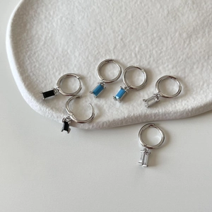 Detail of 925 sterling silver hoop earrings with rectangular zirconia drops in three colors