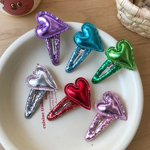 Set di 6 fermagli per capelli con cuori glitterati per bambine su un piatto bianco