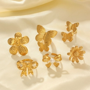 Vintage 18k gold plated butterfly and flower ring set displayed on beige silk fabric