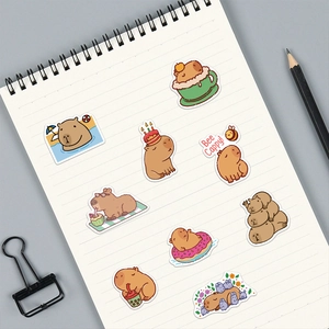 Close-up of cute cartoon capybara stickers on a spiral notebook with a pencil and clip