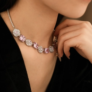 Close-up of silver-tone necklace with pink zircon floral and square pendant on model