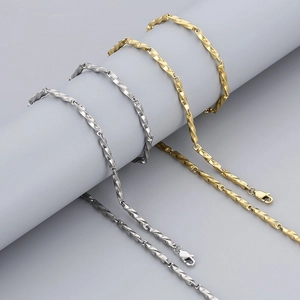 Detail of twisted curb chain bracelets in gold and silver steel on a grey stand