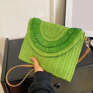 Detail of green raffia woven clutch bag with brown leather strap and tassel trim decoration