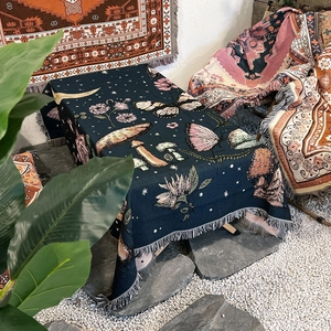 Detail of woven boho blanket with mushrooms, butterflies, flowers and fringe texture