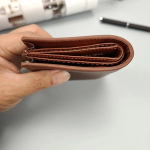 Vista lateral de la cartera de cuero marrón mostrando ranuras para tarjetas y costuras