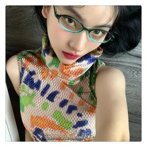 Detail of teal oval glasses frames paired with a high-neck sleeveless knit jacquard top