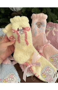 Detailed close-up of fluffy coral fleece socks with cute animal embroidery and pink bows