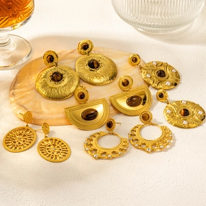 Bohemian gold-plated earrings set with natural brown stones and pearls on stone tray