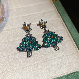 Détail de boucles d'oreilles sapin de Noël avec cristaux colorés et étoile dorée