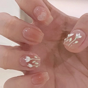 Macro view of short oval press-on nails with white tulip art and silver glitter accents