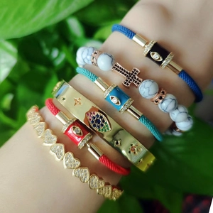 Bohemian stackable evil eye braided bracelets and gold star cuff on model's wrist