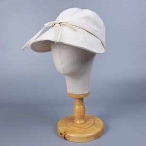 Detail view of beige nylon sun hat with a decorative ribbon bow on a display stand