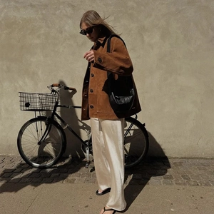 Détail d'une veste vintage marron assortie à un pantalon en satin sur mur beige
