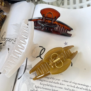 Detailed view of large amber, cream and olive hair claws with durable golden metal springs