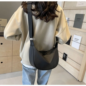 Rear view of model wearing a black crescent nylon crossbody bag with wide shoulder strap