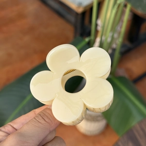 Détail d'une pince à cheveux fleur crème au design à 5 pétales et finition en résine