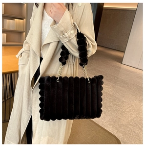Detail of black plush tote bag with wave texture and elegant gold chain strap