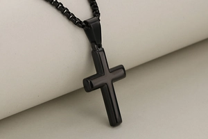 Detail shot of a minimalist black polished stainless steel cross pendant with matching chain