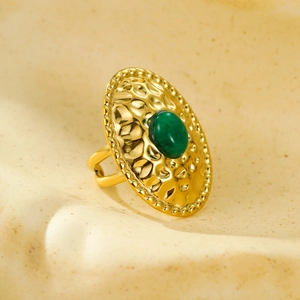 Detailed macro shot of vintage gold oval ring with green stone and hammered texture