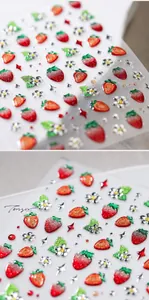 Gros plan de stickers 3D pour ongles aux fraises, paillettes et détails floraux