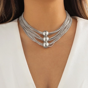 Close-up of a silver multi-layer necklace with three polished spheres on a model's neck