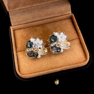 Macro shot of irregular floral stud earrings with rhinestones and pearls in a jewelry box