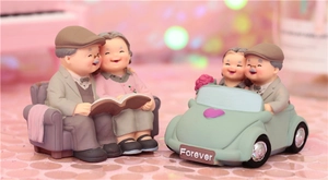 Detail of resin elderly couple figurines sitting on sofa and in vintage car decoration