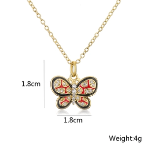 Detail shot of a 18K gold-plated butterfly pendant with red enamel and crystals