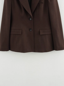 Detail of dark brown blazer featuring double-button closure and classic flap pockets