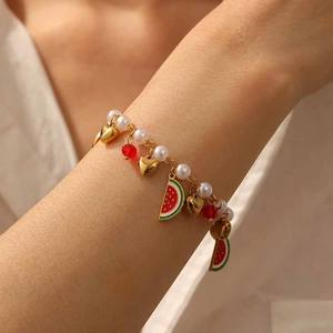 Detail of beaded pearl bracelet with heart and watermelon charms on woman's wrist