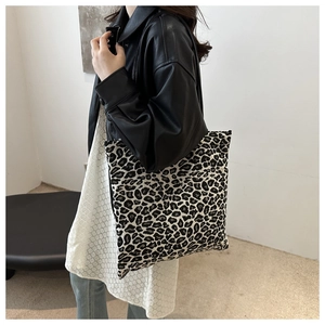 Detailed view of leopard print canvas tote bag with black straps on fashion model