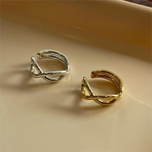 Detailed close-up of twisted wave rings in polished gold and silver minimalist finishes