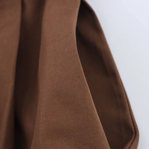 Detailed macro view of dark brown twill fabric texture on elegant belted dress