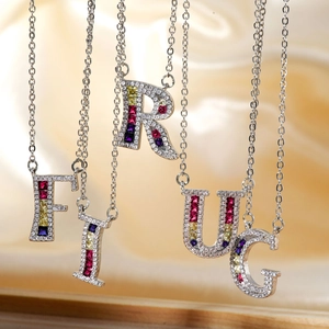 Silver letter pendants F, I, R, U, G with colorful gemstones on gold silk background