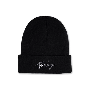 Close-up of black knit beanie featuring white Baby embroidery and ribbed texture detail