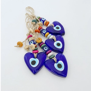 Detail of four heart-shaped blue evil eye glass ornaments with wood beads and hemp rope