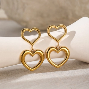 Double heart pendant earrings in 18K gold plated stainless steel on white pedestal